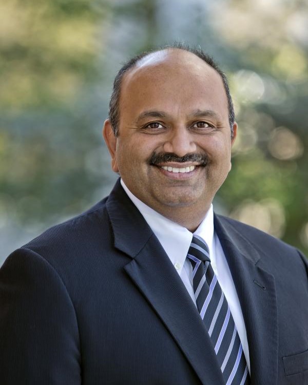 Headshot of Amitabh Varshney, a man smiling wearing a dark suit and striped tie