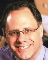 Headshot of Don Millard, a man smiling wearing glasses and a purple shirt