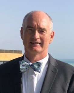 Headshot of Lawrence Schuette, a man smiling wearing a suit and bowtie
