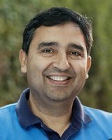Headshot of Rajiv Laroia, a man smiling wearing a blue polo shirt