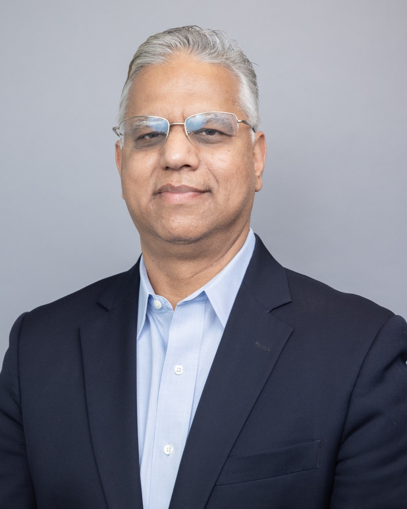 Headshot of Satyandra Gupta, a man smiling wearing glasses, a dark suit, and a light shirt