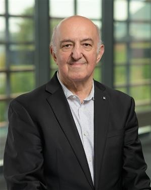Headshot of Tamer Basar, a man smiling wearing a dark suit and light shirt